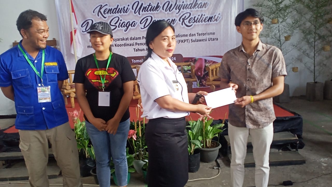 Lurah Kinilow Satu, Sisca Mangundap, S.Kep saat memberikan hadiah kepada Miracle Lumintang selaku Juara 1 Lomba Cerdas Cermat Kebangsaan